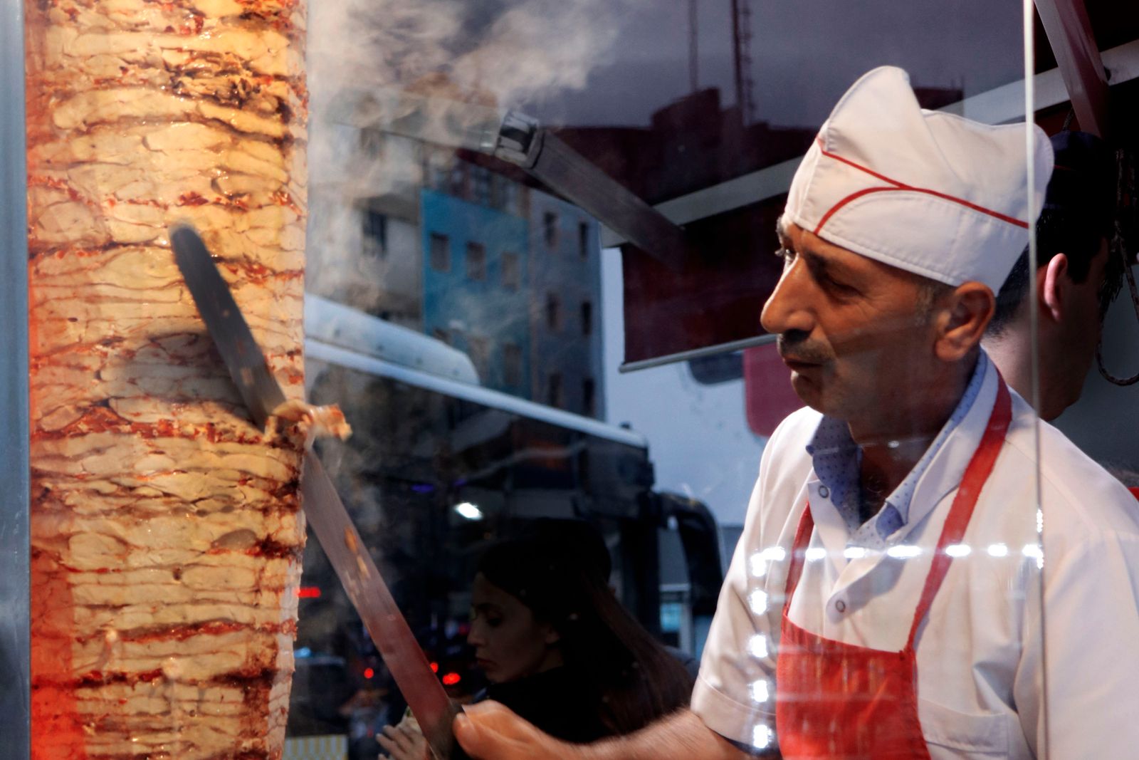 Dönerfleisch wird am Drehspieß hinter der Theke geschnitten